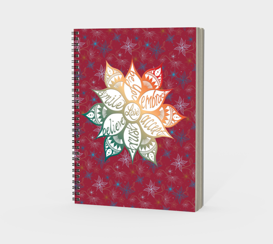 A spiral-bound notebook with a colorful floral design on the cover and the word 'love' in different languages.